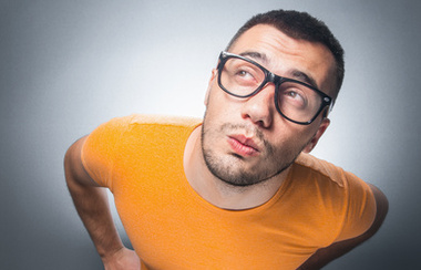 Zbunjeni mladi smiješni muškarac. Pogled iznad. Štreber gleda gore.