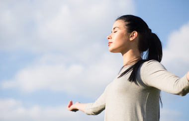 Zgodna žena se opušta na pozadini slobode i plavog neba