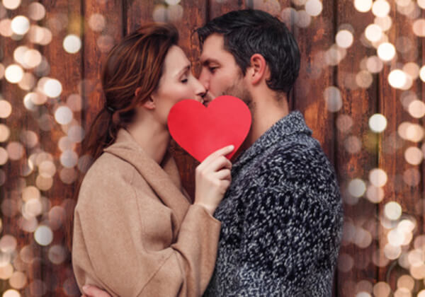 Dvoje zaljubljenih ljudi koji drze crveno srce u ruci.
