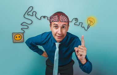 Poslovni čovjek se smiješi i podiže kažiprst prema gore, žice za punjenje pojačivača mozga i skicira infografiku